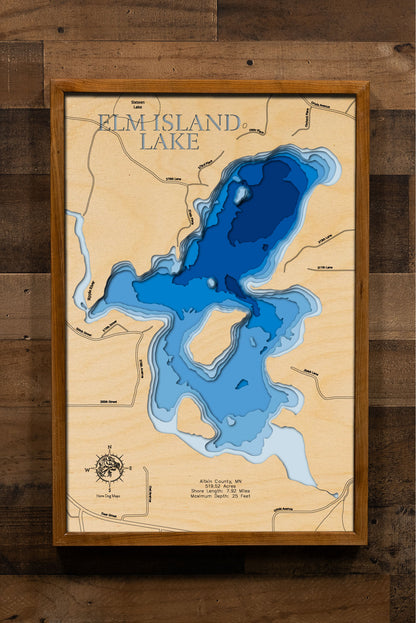  laser-cut, layered wooden map of Elm Island Lake in Aitkin County, Minnesota. The shape of the lake, with its 7.92-mile shoreline, is visible within the central Minnesota landscape. The varying depths of the lake, reaching a maximum of 25 feet, are represented by different layers of wood.