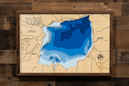 A highly detailed, laser-cut, and multi-layered wooden map of Ennis Lake, a reservoir in Madison County, Montana. The map shows the lake's distinct shape and its location on the Madison River. The varying depths of the lake, reaching a maximum of 20 feet, are represented by different layers of wood, illustrating its impressive underwater topography.