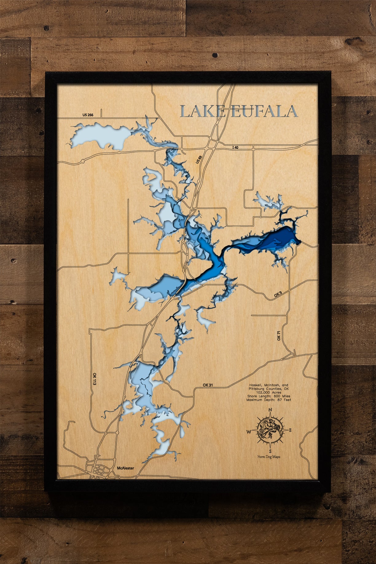 An exquisitely detailed, laser-cut, multi-layered wooden map of Lake Eufaula in McIntosh and Pittsburg Counties, Oklahoma. The map displays the reservoir's expansive 102,000-acre surface, depth contours showing the 87-foot maximum depth, the intricate 600 miles of shoreline with sandy beaches and wooded coves, and the Eufaula Dam on the Canadian River.