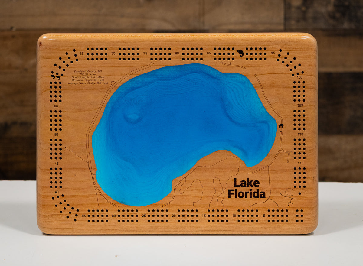 A rectangular wooden plaque featuring an embossed map design with a bright blue resin-filled shape representing Lake Florida, shown on a white surface against a dark wood background.