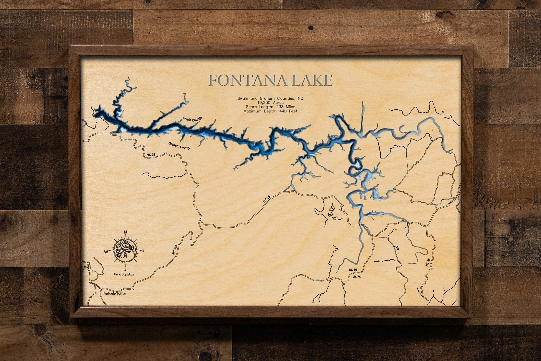 A laser-cut, layered wooden map of Fontana Lake in North Carolina. The distinct, elongated, and winding shape of this large reservoir, with its numerous arms and 238-mile shoreline, is clearly visible as it stretches through Swain and Graham Counties, bordering national park and forest lands. The varying depths of the lake, reaching a maximum of 440 feet, are represented by different layers of wood, illustrating its impressive underwater topography.