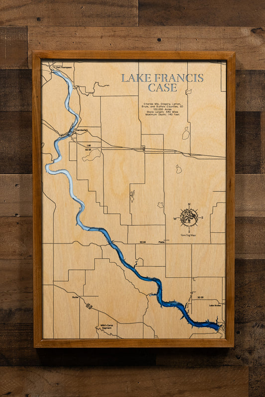 An intricately detailed, multi-layered laser-cut wooden topographic map of Lake Francis Case spanning five South Dakota counties, illustrating the reservoir's impressive 107-mile serpentine course along the Missouri River, depth contours showing the 140-foot maximum depth, the extensive 540-mile shoreline with countless coves and creek arms, Fort Randall Dam at the southern terminus, and major landmarks including Chamberlain, the White River confluence, and Big Bend Dam.