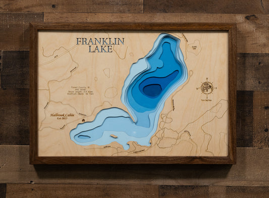 A laser-cut, layered wooden map of Franklin Lake in Forest County, Wisconsin. The distinct shape of this natural lake, with its 3.9-mile shoreline, is clearly visible within the forested landscape of northern Wisconsin. The varying depths of the lake, reaching a maximum of 40 feet, are represented by different layers of wood, illustrating its impressive underwater topography.
