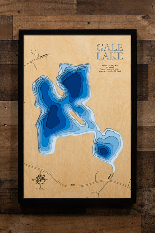 A precision laser-cut, multi-layered wooden map of Gale Lake in Itasca County, Minnesota, a secluded 73-acre lake nine miles southeast of Bigfork with no developed public access. The natural wood top layer captures 2 miles of forested shoreline in fine detail, while a light-to-dark blue gradient conveys the lake's 50-foot depth. A handcrafted statement piece for any Minnesota Northwoods cabin, lake home, or outdoor enthusiast's wall.