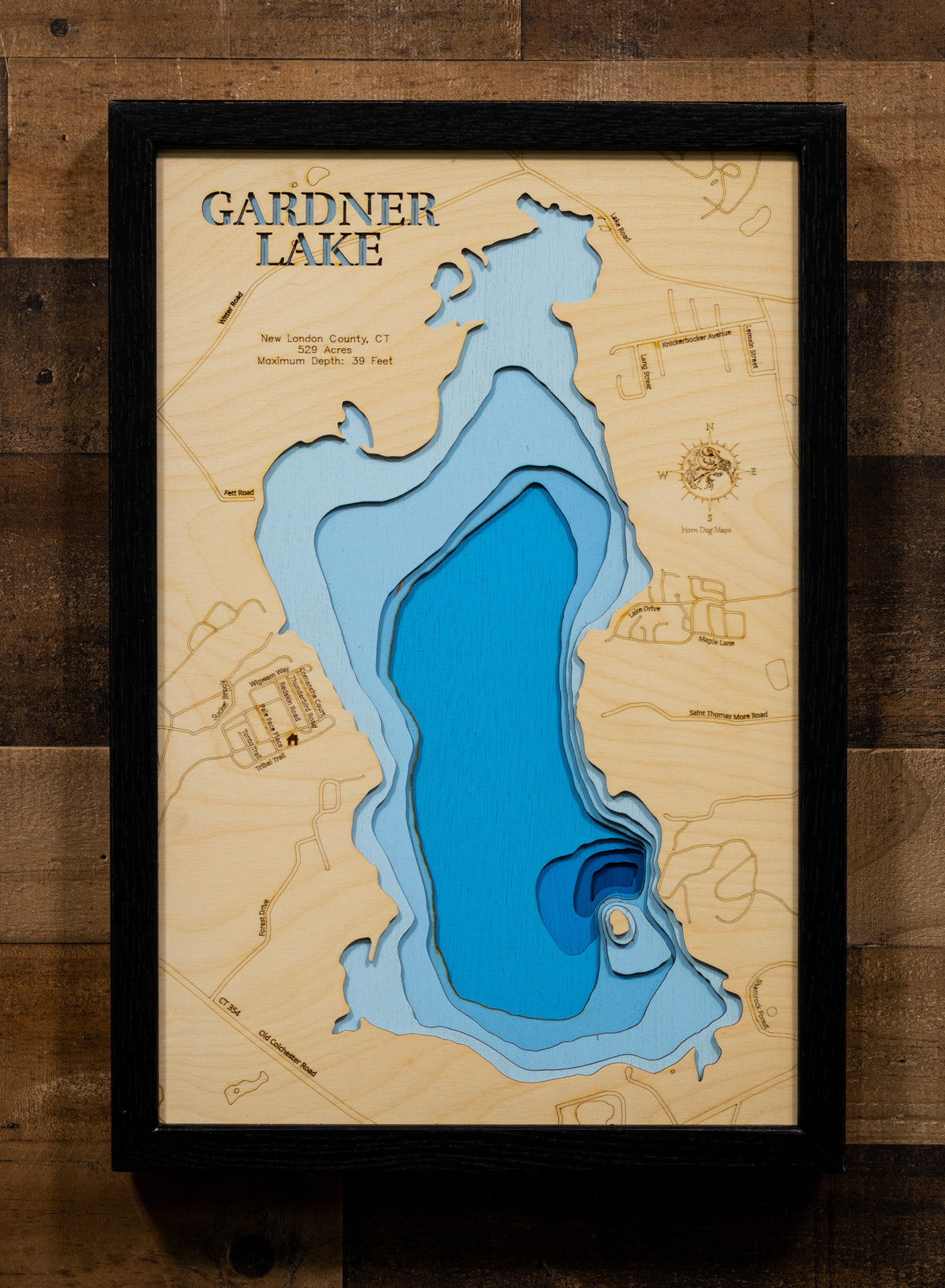 A precision laser-cut, multi-layered wooden map of Gardner Lake in New London County, Connecticut, a 529-acre natural lake spanning Salem, Montville, and Bozrah near Mystic and the Thames River valley. The natural wood top layer captures the lake's shoreline and Minnie Island in fine detail, while a light-to-dark blue gradient conveys its 39-foot depth. A handcrafted statement piece for any Connecticut lake home, cabin, or New England outdoor enthusiast's wall.