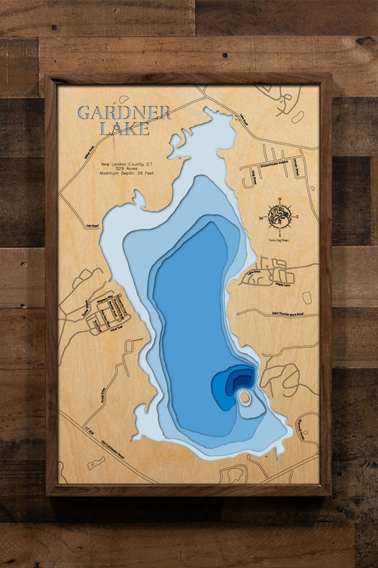 A precision laser-cut, multi-layered wooden map of Gardner Lake in New London County, Connecticut, a 529-acre natural lake spanning Salem, Montville, and Bozrah near Mystic and the Thames River valley. The natural wood top layer captures the lake's shoreline and Minnie Island in fine detail, while a light-to-dark blue gradient conveys its 39-foot depth. A handcrafted statement piece for any Connecticut lake home, cabin, or New England outdoor enthusiast's wall.