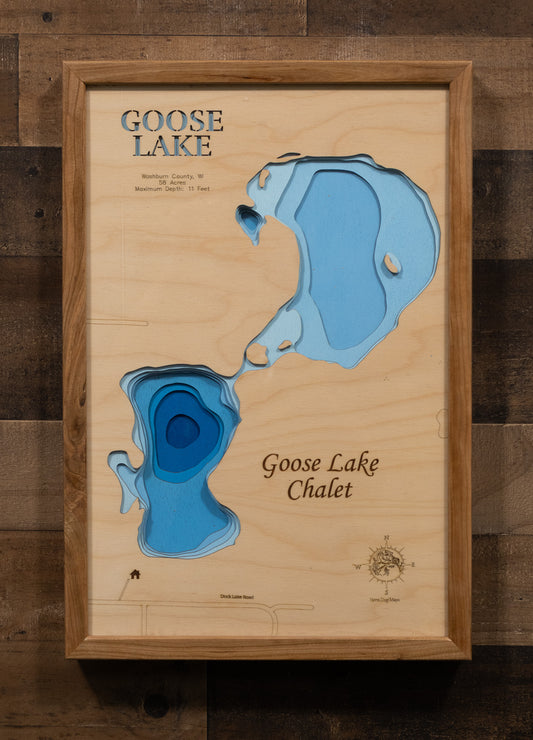 A highly detailed, laser-cut, and multi-layered wooden map of Goose Lake, a natural lake in Washburn County, Wisconsin. The map shows the lake's distinct shape, its 1.9-mile shoreline, and the surrounding natural area. The varying depths of the lake, reaching a maximum of 16 feet, are represented by different layers of wood.