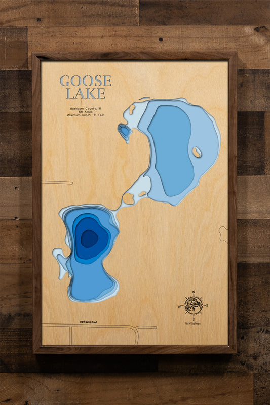 A highly detailed, laser-cut, and multi-layered wooden map of Goose Lake, a natural lake in Washburn County, Wisconsin. The map shows the lake's distinct shape, its 1.9-mile shoreline, and the surrounding natural area. The varying depths of the lake, reaching a maximum of 16 feet, are represented by different layers of wood.
