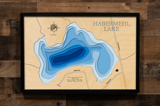 A highly detailed, laser-cut, and multi-layered wooden map of Habermehl Lake, a natural lake in the Parry Sound District of Ontario. The map shows the lake's distinct shape and its 1.68-mile shoreline. The varying depths of the lake, reaching a maximum of 50 feet, are represented by different layers of wood.