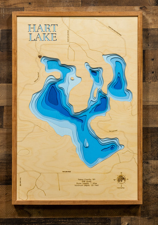 A meticulously detailed, laser-cut, multi-layered wooden topographical map of Hart Lake in Itasca County, Minnesota, showcasing the lake's 328-acre surface with intricate depth contours illustrating wetland inlets and the transition from shallow areas to the 55-foot maximum depth. The natural wood top layer frames seven miles of precisely rendered shoreline and the outlet to Swan Lake, while graduated blue layers create a striking visual depth gradient.