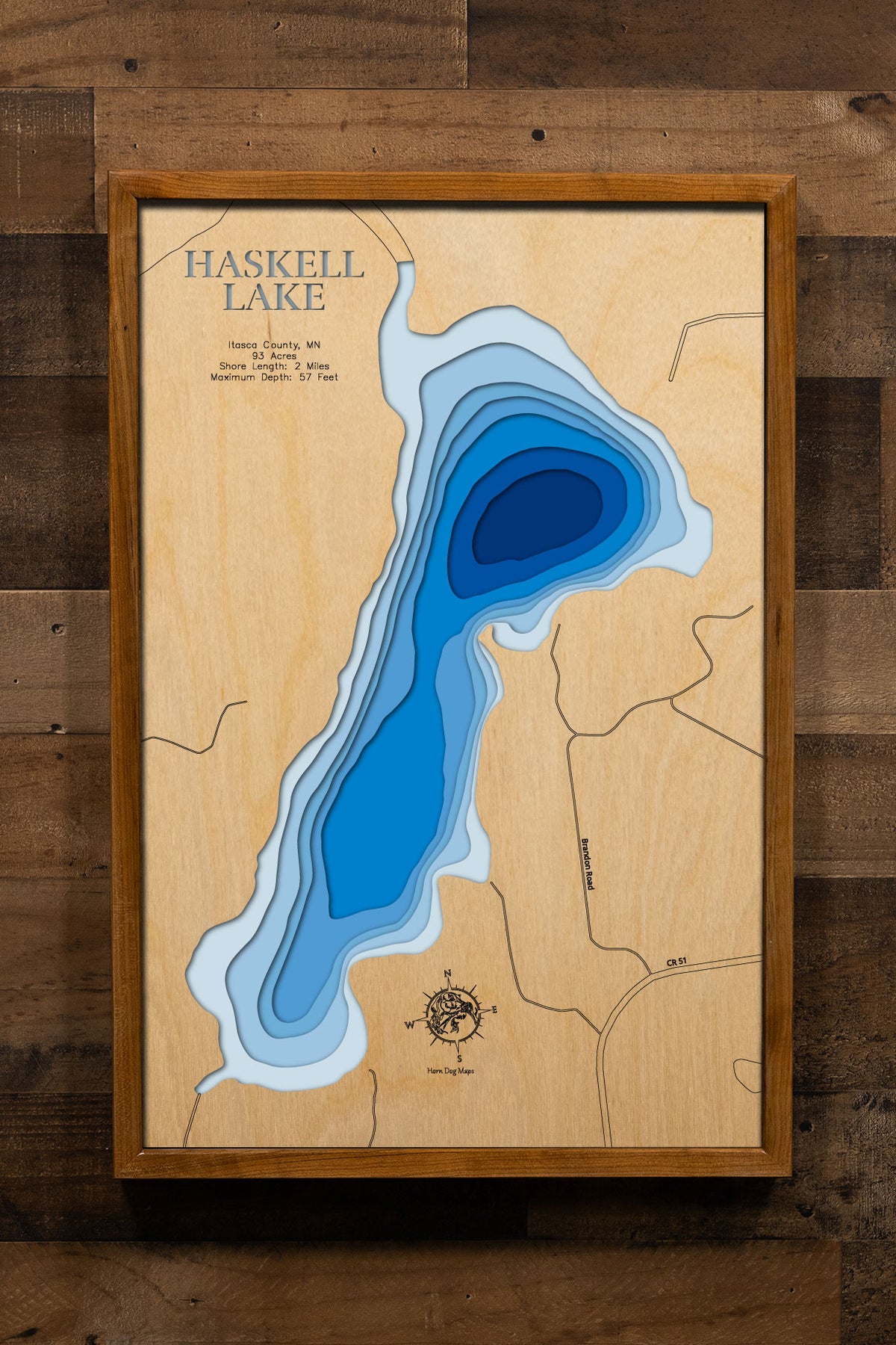 A precision laser-cut, multi-layered wooden map of Haskell Lake in Itasca County, Minnesota, a 93-acre clear-water lake 15 miles north of Bovey part of a navigable chain with Scrapper and Balsam Lakes. The natural wood top layer captures 2 miles of shoreline in fine detail, while a light-to-dark blue gradient conveys the lake's impressive 57-foot depth. A handcrafted statement piece for any Minnesota lake cabin, home, or outdoor enthusiast's wall.