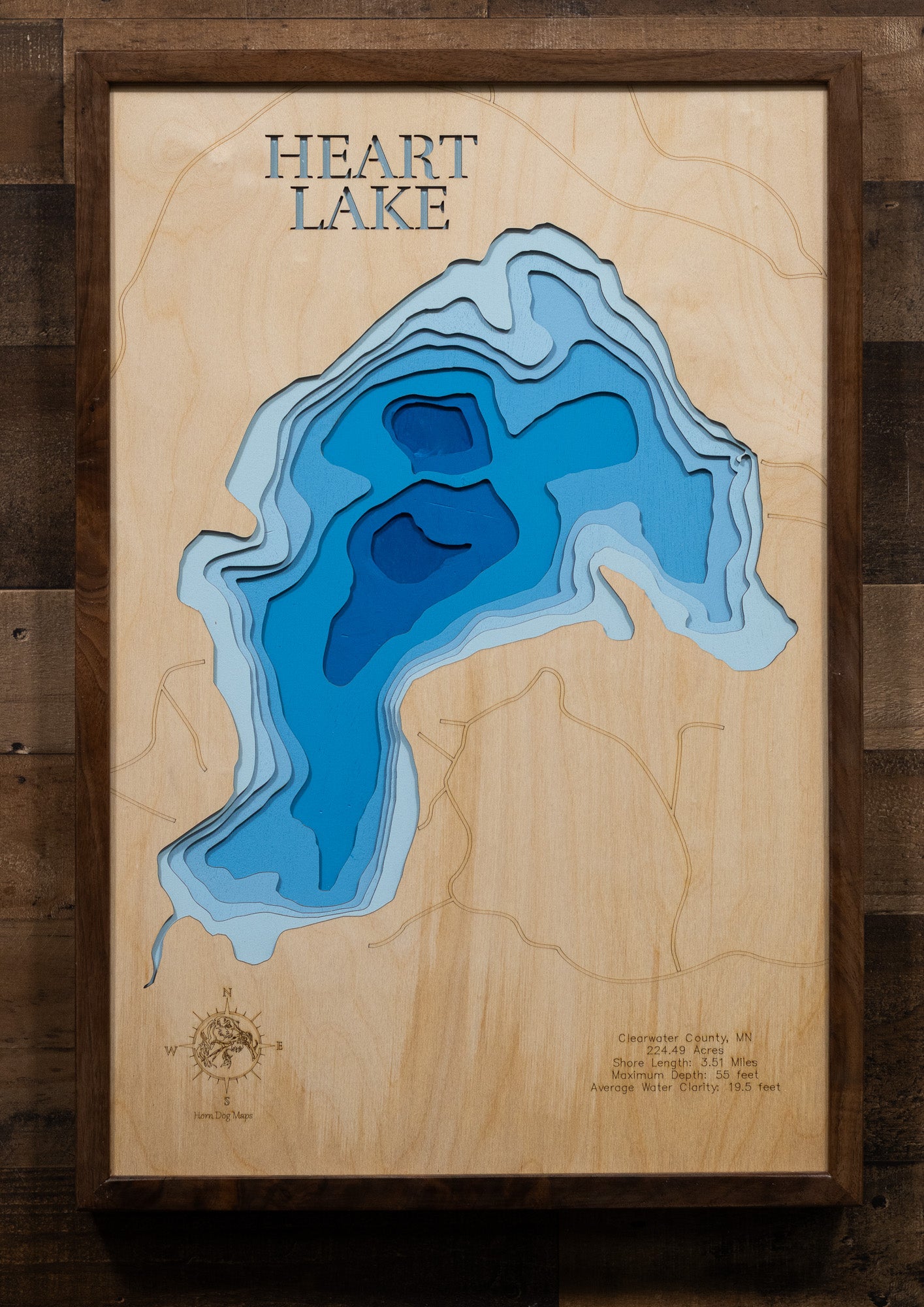 A laser-cut, layered wood map of Heart Lake, Minnesota, illustrating its winding shoreline and forested surroundings in Clearwater County.