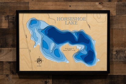 A precision laser-cut, multi-layered wooden map of Horseshoe Lake in Barron County, Wisconsin, just north of Cumberland. The natural wood top layer captures the lake's distinctive horseshoe-shaped shoreline in fine detail, while a light-to-dark blue gradient conveys its 19-foot depth. A handcrafted statement piece for any Wisconsin lake cabin, home, or outdoor enthusiast's wall.