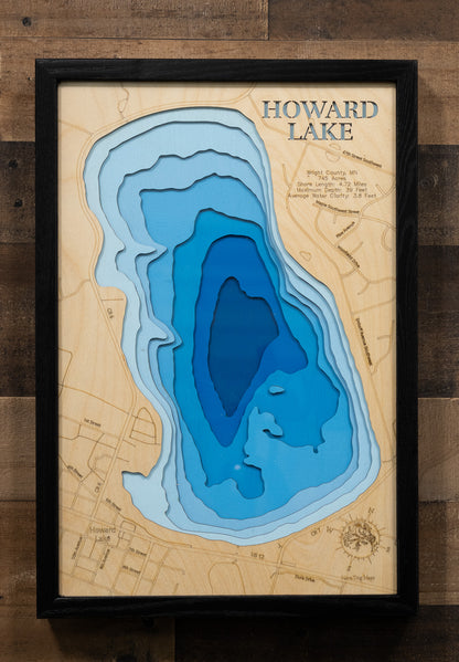 A laser-cut, layered wooden map of Howard Lake in Wright County, Minnesota. The distinct shape of this natural lake, with its 4.72-mile shoreline, is clearly visible within the forested landscape of central Minnesota. The varying depths of the lake, reaching a maximum of 39 feet, are represented by different layers of wood, illustrating its impressive underwater topography.