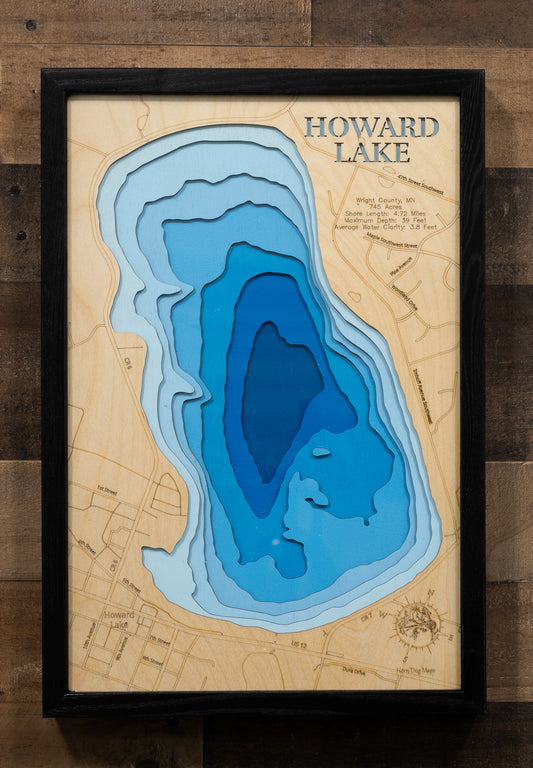 A laser-cut, layered wooden map of Howard Lake in Wright County, Minnesota. The distinct shape of this natural lake, with its 4.72-mile shoreline, is clearly visible within the forested landscape of central Minnesota. The varying depths of the lake, reaching a maximum of 39 feet, are represented by different layers of wood, illustrating its impressive underwater topography.