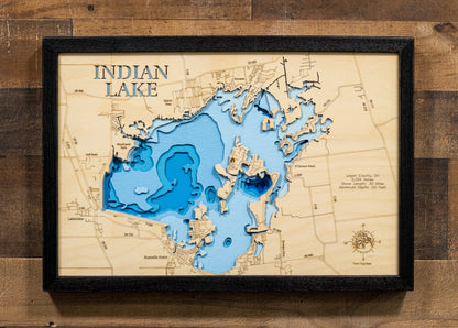 A highly detailed, laser-cut, and multi-layered wooden map of Indian Lake in Logan County, Ohio. The map showcases the reservoir's distinctive 5,104-acre shape with the iconic Indian Isles island chain arcing through its center, depth contours illustrating the shallow 20-foot maximum depth, and the intricate 30 miles of shoreline with numerous bays and inlets.