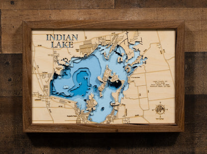 A highly detailed, laser-cut, and multi-layered wooden map of Indian Lake in Logan County, Ohio. The map showcases the reservoir's distinctive 5,104-acre shape with the iconic Indian Isles island chain arcing through its center, depth contours illustrating the shallow 20-foot maximum depth, and the intricate 30 miles of shoreline with numerous bays and inlets.