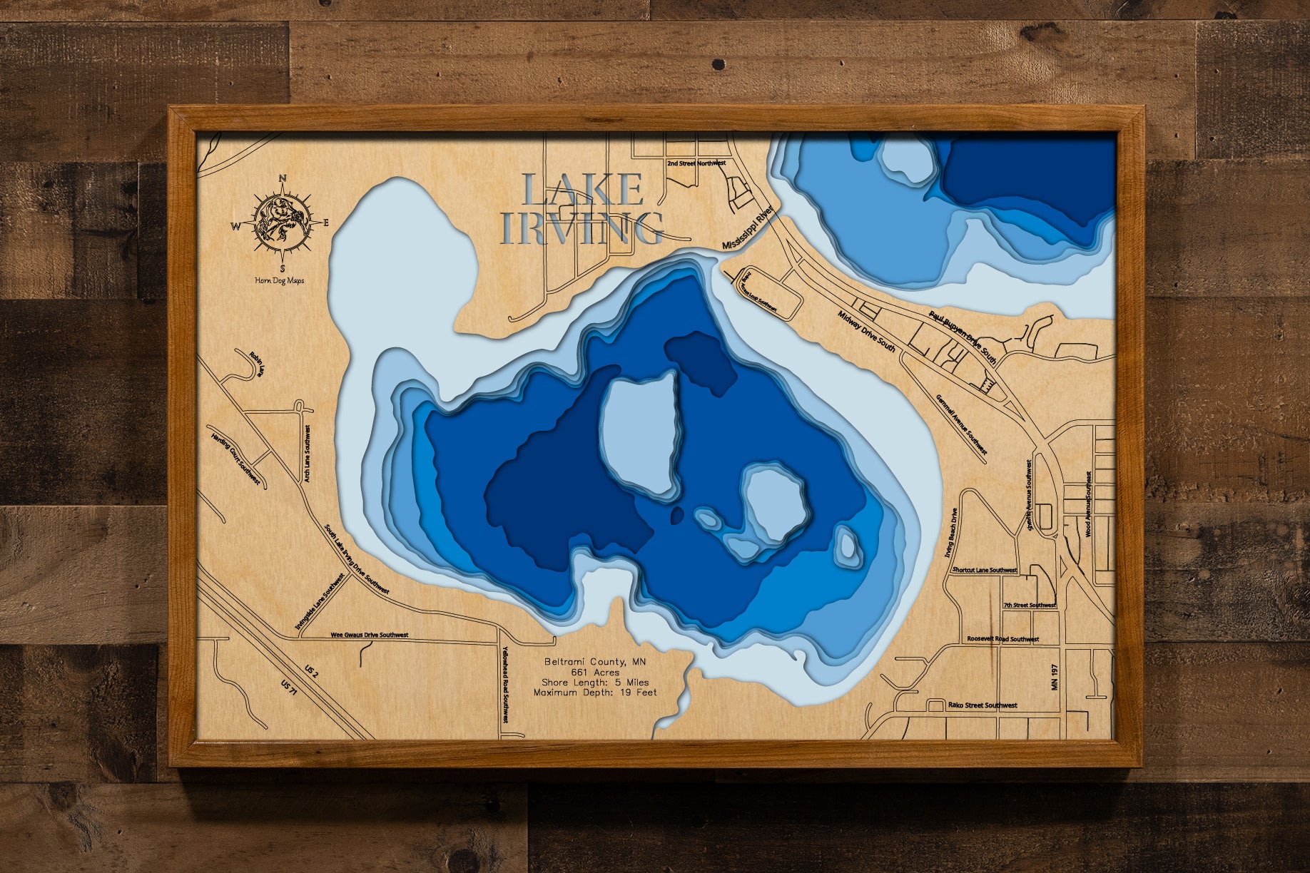 A meticulously detailed, laser-cut, multi-layered wooden topographical map of Lake Irving in Beltrami County, Minnesota, showcasing the lake's 661-acre surface area along the Mississippi River with depth contours from the 10-foot average depth to the 19-foot maximum. The natural wood top layer frames five miles of intricate shoreline detail and river connections, while graduated blue layers create a striking visual depth gradient.