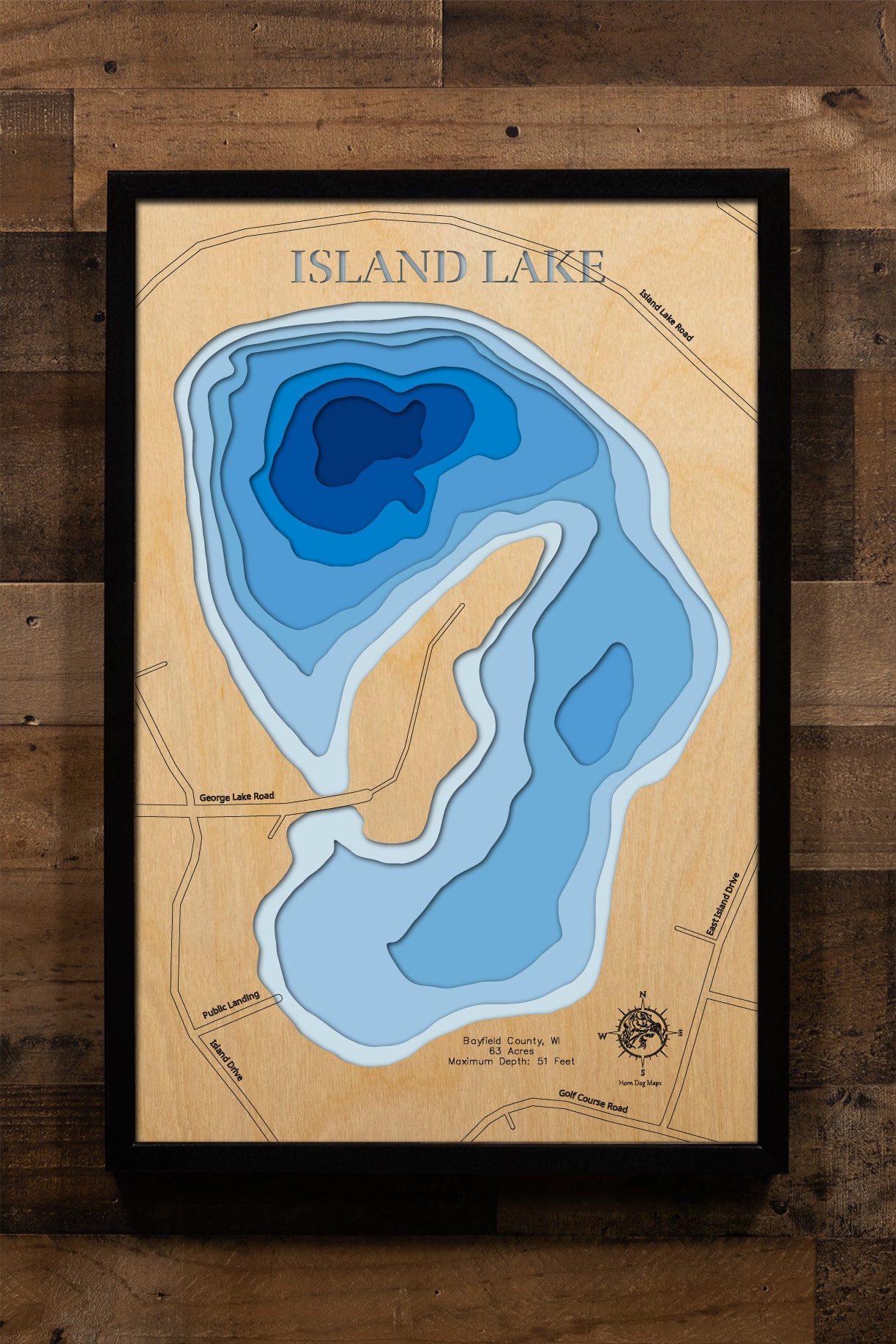 A precision laser-cut, multi-layered wooden map of Island Lake in Bayfield County, Wisconsin. The natural wood top layer captures the lake's intimate shoreline in fine detail, while a light-to-dark blue gradient highlights the water's depth and dimension. A distinctive, rustic statement piece crafted for cabin walls, fishing lodges, or any Wisconsin Northwoods-inspired living space.