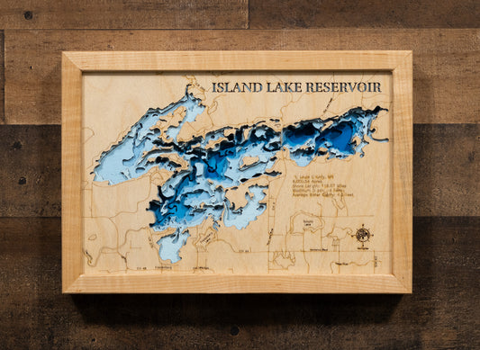 A laser-cut, layered wooden map of Island Lake Reservoir in St. Louis County, Minnesota. The distinct shape of this large reservoir, with its 116.07-mile shoreline and numerous islands, is clearly visible within the forested landscape of northern Minnesota. The varying depths of the reservoir, reaching a maximum of 94 feet, are represented by different layers of wood, illustrating its impressive underwater topography.