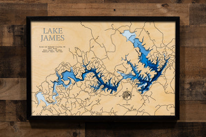A laser-cut, layered wooden map of Lake James in North Carolina. The distinct shape of this large reservoir, with its numerous arms and 150-mile shoreline, is clearly visible as it spans Burke and McDowell Counties. The varying depths of the lake, reaching a maximum of 120 feet, are represented by different layers of wood, illustrating its impressive underwater topography.