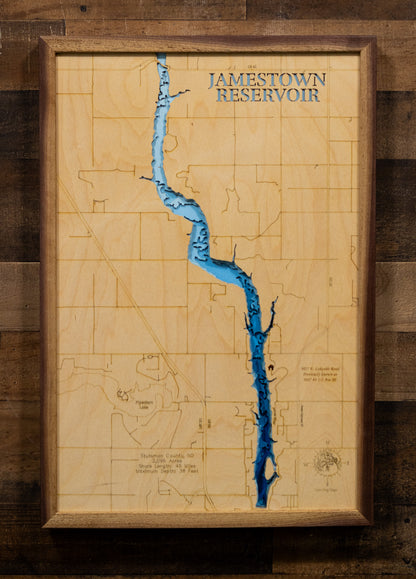 A highly detailed, laser-cut, and multi-layered wooden map of Jamestown Reservoir in Stutsman County, North Dakota. The map highlights the 2,095-acre reservoir's winding 8-mile length along the James River valley, with depth contours showing the 38-foot maximum depth, the unique peninsula and island features, and the intricate 45 miles of shoreline.