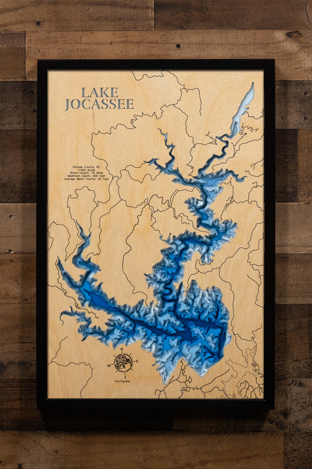 A breathtaking, laser-cut, multi-layered wooden map of Lake Jocassee in Oconee County, South Carolina, capturing the reservoir's serpentine arms extending into mountain coves, dramatic depth contours descending to 300 feet, the 75 miles of undeveloped forested shoreline, and the four major river inflows from the Blue Ridge Mountains.