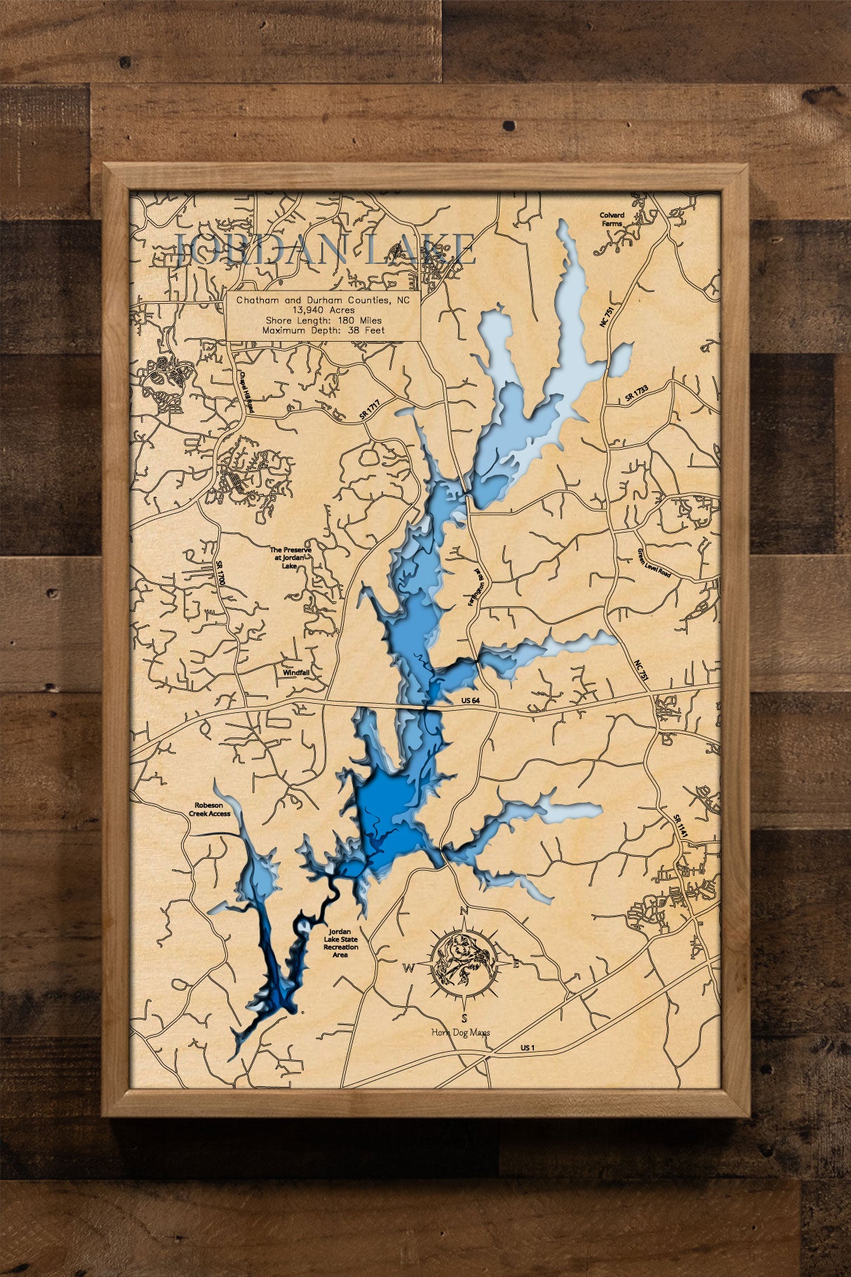 A laser-cut, layered wooden map of Jordan Lake in North Carolina. The expansive and highly irregular shape of this large reservoir, with its numerous arms and 180-mile shoreline, is clearly visible as it winds through Chatham, Durham, Wake, and Harnett Counties. The varying depths of the lake, reaching a maximum of 110 feet, are represented by different layers of wood, illustrating its impressive underwater topography.