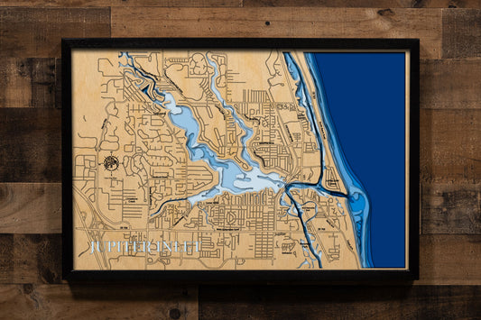 A laser-cut, layered wood map of Jupiter Inlet, Florida, illustrating its winding waterways, coastal shoreline, and surrounding landscapes in Palm Beach and Martin Counties.