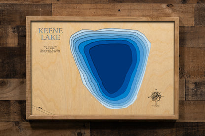 A detailed, laser-cut, multi-layered wooden map of Keene Lake in Pine County, Minnesota, showcasing the intimate 9.22-acre lake with half a mile of natural shoreline near Hinckley. The topographic design features natural wood layers highlighting the surrounding pine forest landscape and graduated blue water layers illustrating depths to the 17-foot maximum.