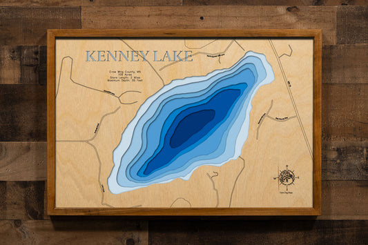 A precision laser-cut, multi-layered wooden map of Kenney Lake in Crow Wing County, Minnesota, near Garrison on the western edge of the Mille Lacs area. The natural wood top layer captures 2 miles of shoreline in fine detail, while a light-to-dark blue gradient conveys the lake's impressive 55-foot depth. A handcrafted statement piece for any Minnesota lake cabin, home, or outdoor enthusiast's wall.