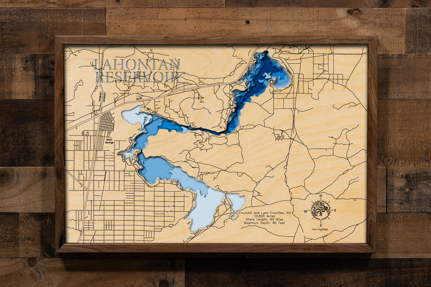 A laser-cut, layered wooden map of Lahontan Reservoir, located in Churchill and Lyon Counties, Nevada. The shape of the reservoir, formed by the Carson River, is clearly visible within the northwestern Nevada landscape. The varying depths of the lake, reaching a maximum of 85 feet, are represented by different layers of wood, creating a three-dimensional effect of this important Nevada water body.