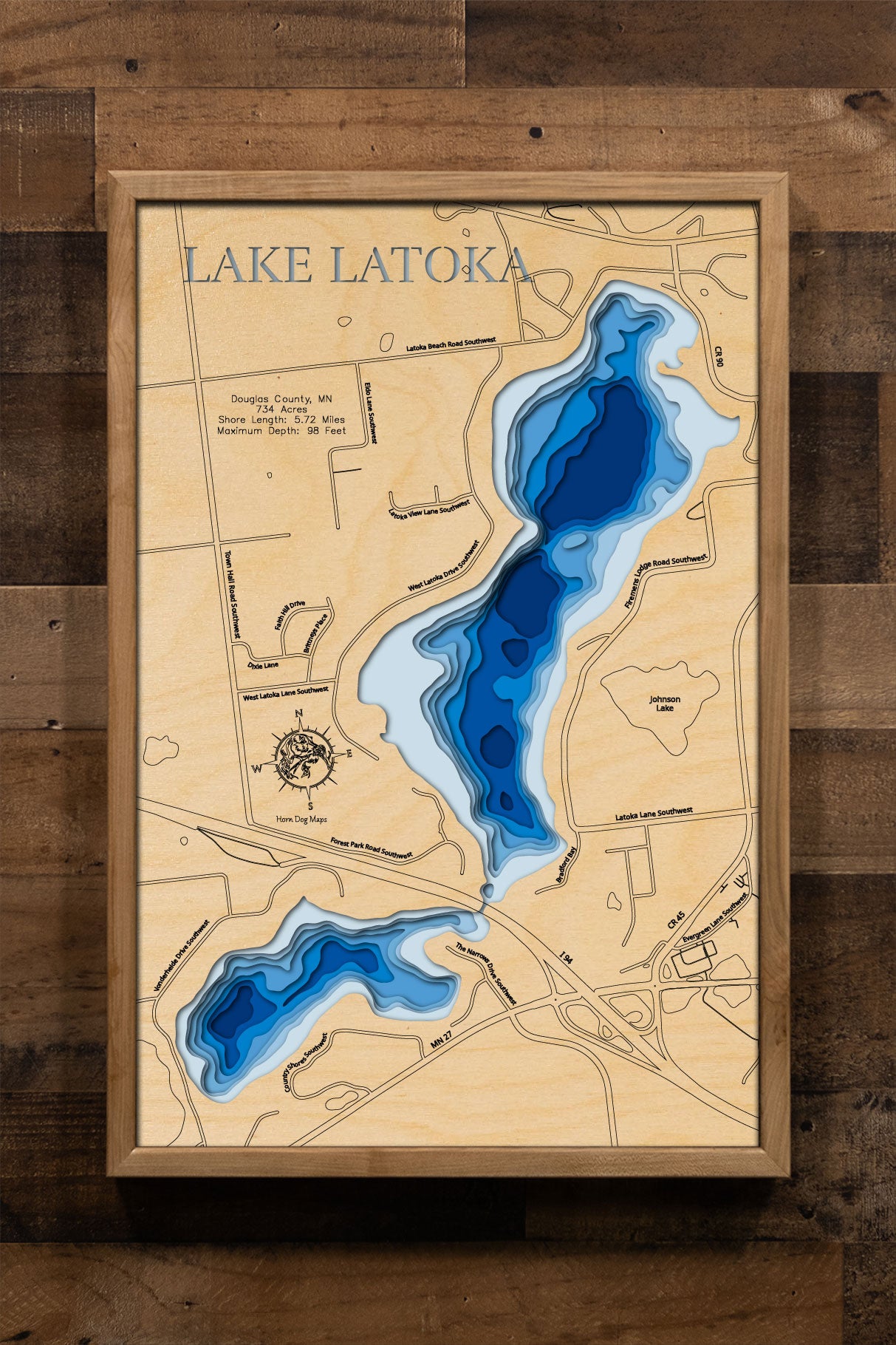 A laser-cut, layered wooden map of Lake Latoka in Douglas County, Minnesota. The distinct shape of this natural lake, with its 5.72-mile shoreline, is clearly visible within the landscape of west-central Minnesota. The varying depths of the lake, reaching a maximum of 98 feet, are represented by different layers of wood, illustrating its impressive underwater topography.