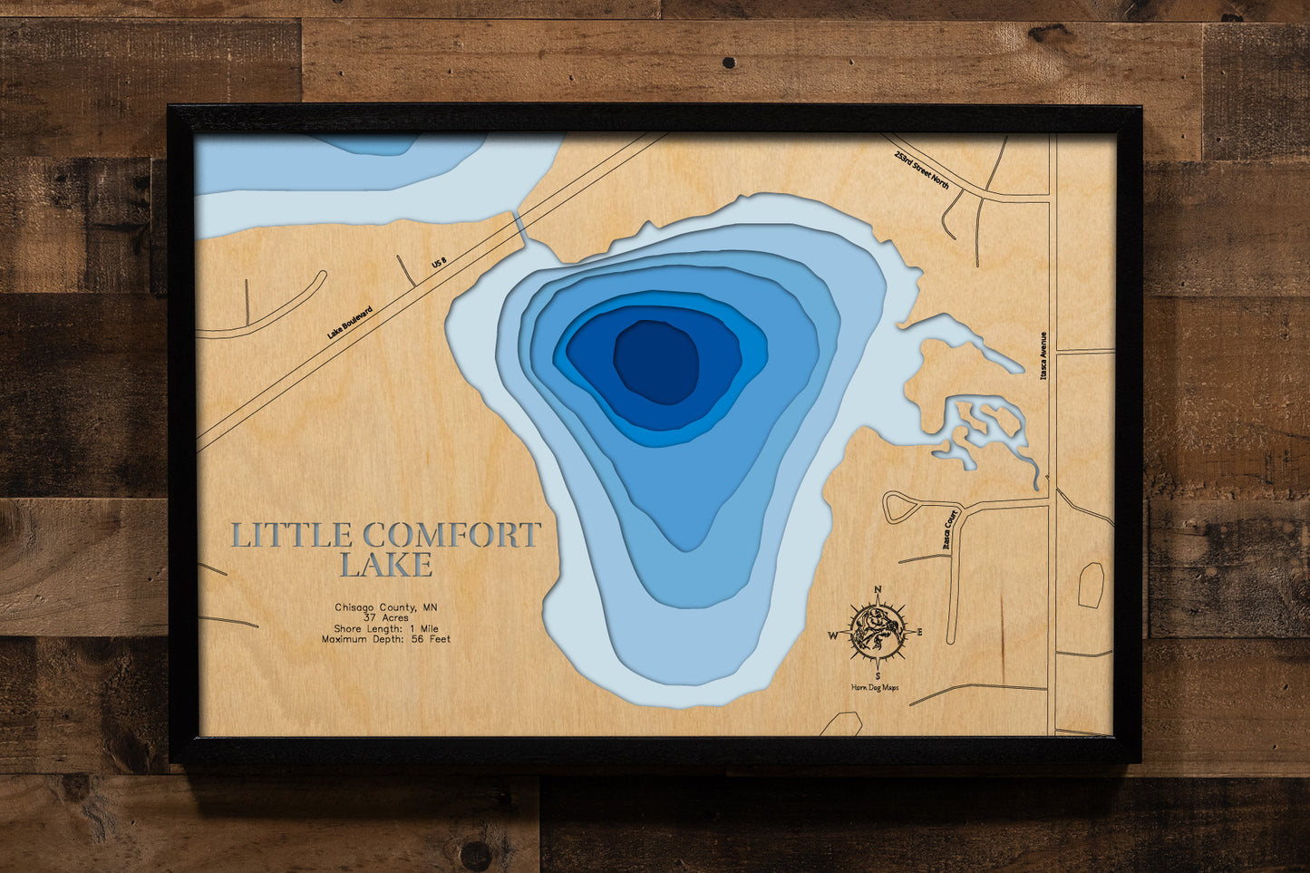 A precision laser-cut, multi-layered wooden map of Little Comfort Lake in Chisago County, Minnesota — a small, private lake of just 37 acres with a striking maximum depth of 56 feet. The natural wood top layer captures its intimate shoreline in fine detail, while a light-to-dark blue gradient conveys the lake's surprising depth. A handcrafted statement piece for any Minnesota lake home, cabin, or outdoor enthusiast's wall.