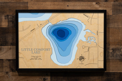 A precision laser-cut, multi-layered wooden map of Little Comfort Lake in Chisago County, Minnesota — a small, private lake of just 37 acres with a striking maximum depth of 56 feet. The natural wood top layer captures its intimate shoreline in fine detail, while a light-to-dark blue gradient conveys the lake's surprising depth. A handcrafted statement piece for any Minnesota lake home, cabin, or outdoor enthusiast's wall.