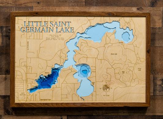 A wooden 3D map wall art piece of Little Saint Germain Lake, featuring layered wood relief and colored water sections in blue and light blue, mounted on a dark wood plank wall.