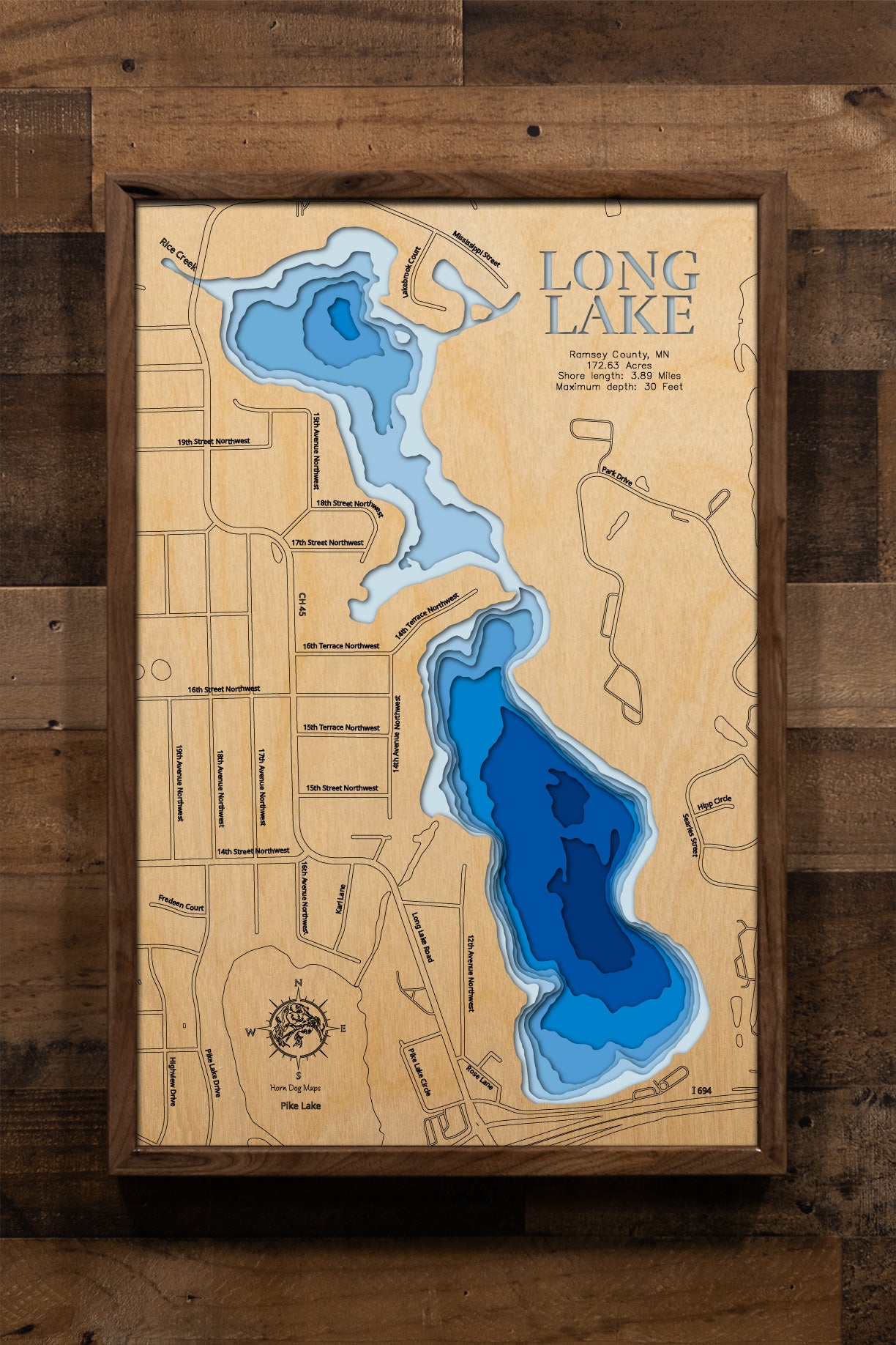 A highly detailed, laser-cut, and multi-layered wooden map of Long Lake, a natural lake in Ramsey County, Minnesota. The map shows the lake's distinct shape and its 4.88-mile shoreline, highlighting its location near New Brighton and Arden Hills. The varying depths of the lake, reaching a maximum of 36 feet, are represented by different layers of wood.