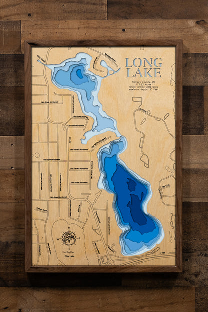 A highly detailed, laser-cut, and multi-layered wooden map of Long Lake, a natural lake in Ramsey County, Minnesota. The map shows the lake's distinct shape and its 4.88-mile shoreline, highlighting its location near New Brighton and Arden Hills. The varying depths of the lake, reaching a maximum of 36 feet, are represented by different layers of wood.