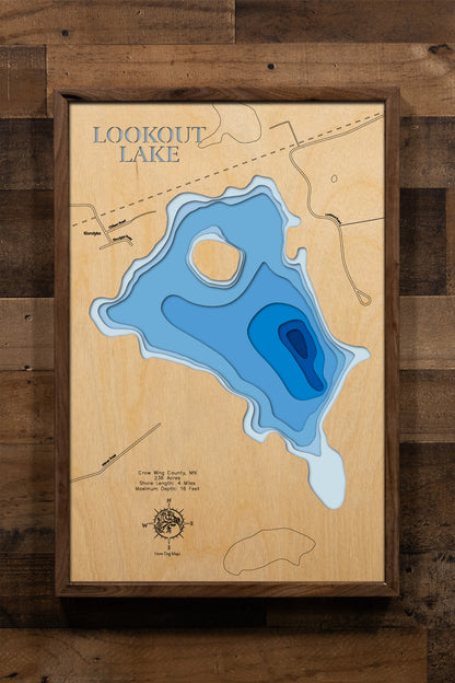 A detailed, laser-cut, multi-layered wooden map of Lookout Lake in Crow Wing County, Minnesota, showcasing the shallow 236-acre lake with 4 miles of shoreline near Crosby, Ironton, and Deerwood in the Cuyuna mining region. The topographic design features natural wood layers highlighting the regenerated forest landscape and graduated blue water layers illustrating the shallow 16-foot maximum depth.