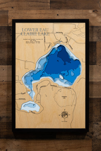 A precision laser-cut, multi-layered wooden map of Lower Eau Claire Lake in Bayfield and Douglas Counties, Wisconsin, a 784-acre Chequamegon National Forest lake and the southernmost link in the 11-lake Eau Claire Chain near Barnes. The natural wood top layer captures 7.78 miles of sandy shoreline in fine detail, while a light-to-dark blue gradient conveys its 41-foot depth. A handcrafted statement piece for any Wisconsin Northwoods cabin, lake home, or outdoor enthusiast's wall.