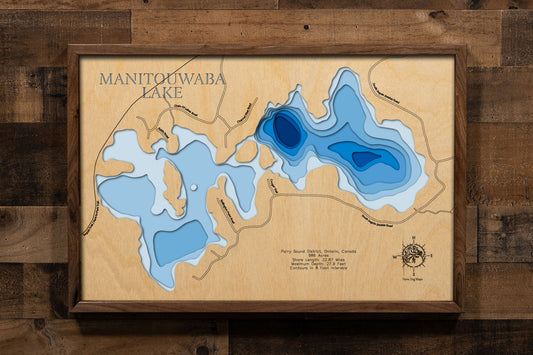 A laser-cut, layered wooden map of Manitouwaba Lake in the Parry Sound District, Ontario, Canada. The distinct, irregular shape of this natural lake, with its 22.87-mile shoreline, is clearly visible within the Canadian Shield landscape. The varying depths of the lake, reaching a maximum of 27.9 feet and detailed by 8-foot contour intervals, are represented by different layers of wood, illustrating its impressive underwater topography.