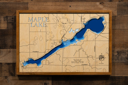 A highly detailed, laser-cut, and multi-layered wooden map of Maple Lake, a natural lake in Polk County, Minnesota. The map shows the lake's distinct shape and its extensive 20.32-mile shoreline. The varying depths of the lake, reaching a maximum of 15 feet, are represented by different layers of wood.