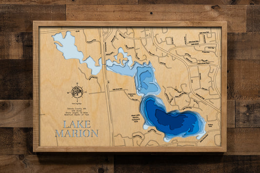 A meticulously crafted, multi-layered laser-cut wooden topographic map of Lake Marion in Dakota County, Minnesota, featuring the three distinct bays across 530 acres, depth contours illustrating the 21-foot maximum depth in the East Bay, the 10 miles of irregular shoreline with numerous small inlets, markers for Antler's Park and Casperson Park with boat launches, the historic Dan Patch Air Rail connection point, and the lake's position within the thriving Lakeville community.