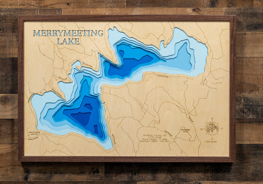 A magnificently detailed, laser-cut, multi-layered wooden topographical map of Merrymeeting Lake in Strafford County, New Hampshire, showcasing the 1,233-acre spring-fed lake's distinctive irregular hourglass shape with dramatic depth contours from the 29-foot average to the impressive 120-foot maximum depth. The natural wood top layer frames 11 miles of intricate shoreline including the dam, Merrymeeting River outlet to Lake Winnipesaukee, and protected conservation lands, while graduated blue layers creat