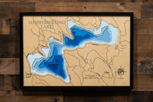 A magnificently detailed, laser-cut, multi-layered wooden topographical map of Merrymeeting Lake in Strafford County, New Hampshire, showcasing the 1,233-acre spring-fed lake's distinctive irregular hourglass shape with dramatic depth contours from the 29-foot average to the impressive 120-foot maximum depth. The natural wood top layer frames 11 miles of intricate shoreline including the dam, Merrymeeting River outlet to Lake Winnipesaukee, and protected conservation lands, while graduated blue layers creat