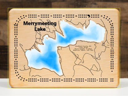A magnificently detailed, laser-cut, multi-layered wooden topographical map of Merrymeeting Lake in Strafford County, New Hampshire, showcasing the 1,233-acre spring-fed lake's distinctive irregular hourglass shape with dramatic depth contours from the 29-foot average to the impressive 120-foot maximum depth. The natural wood top layer frames 11 miles of intricate shoreline including the dam, Merrymeeting River outlet to Lake Winnipesaukee, and protected conservation lands, while graduated blue layers creat