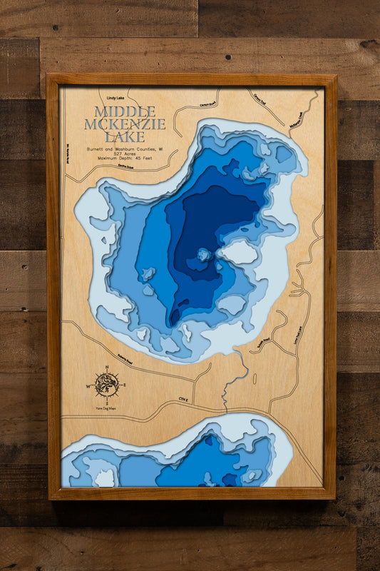 A precision laser-cut, multi-layered wooden map of Middle McKenzie Lake in Burnett and Washburn Counties, Wisconsin. The natural wood top layer captures the shoreline of this clear, hard-bottomed northwest Wisconsin lake in fine detail, while a light-to-dark blue gradient highlights its 45-foot depth. A handcrafted statement piece for any Wisconsin Northwoods cabin, lake home, or outdoor enthusiast's wall.
