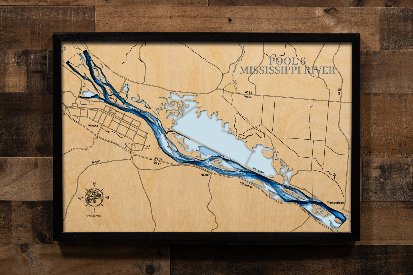 A highly detailed, laser-cut, and multi-layered wooden map of Mississippi River Pool 6, an impoundment on the Upper Mississippi River, spanning Wisconsin and Minnesota. The map illustrates the vast 22,000-acre complex of backwaters, islands, and the deep, navigable main channel. The location of Lock and Dam 6 near Trempealeau, WI, is highlighted on the lower section of the map.