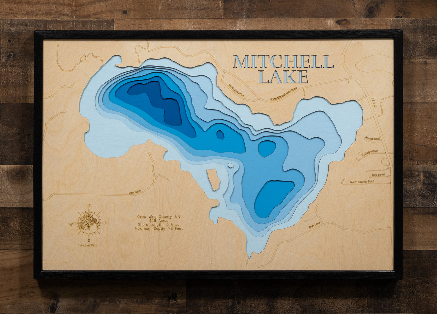 A meticulously detailed, laser-cut, multi-layered wooden map of Mitchell Lake in Crow Wing County, Minnesota, showcasing the distinctive heart-shaped 429-acre lake with 5 miles of natural shoreline. The topographic design features natural wood layers highlighting the stony brook and surrounding forestland, with graduated blue water layers illustrating depths to the 78-foot maximum depth.