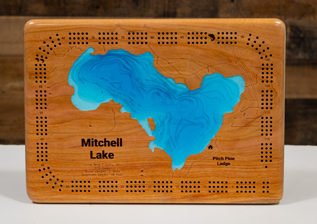 A meticulously detailed, laser-cut, multi-layered wooden map of Mitchell Lake in Crow Wing County, Minnesota, showcasing the distinctive heart-shaped 429-acre lake with 5 miles of natural shoreline. The topographic design features natural wood layers highlighting the stony brook and surrounding forestland, with graduated blue water layers illustrating depths to the 78-foot maximum depth.